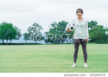 一位日本女性,她是足球迷和支持者,在操場上拿著足球 一位日本女性,她是足球迷和支持者,在操場上拿著足球 102008170