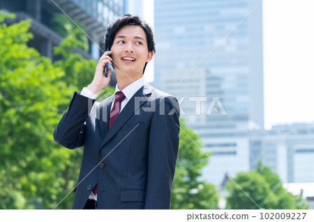 一位穿著西裝的新員工男性商人在辦公區使用智能手機工作 102009227