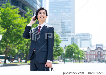 一位穿著西裝的新員工男性商人在辦公區使用智能手機工作 一位穿著西裝的新員工男性商人在辦公區使用智能手機工作 102009228