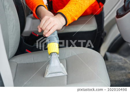 Handyman vacuuming car front textile seat with vacuum cleaner. man cleaning work machine Handyman vacuuming car front textile seat with vacuum cleaner. man cleaning work machine 102010498