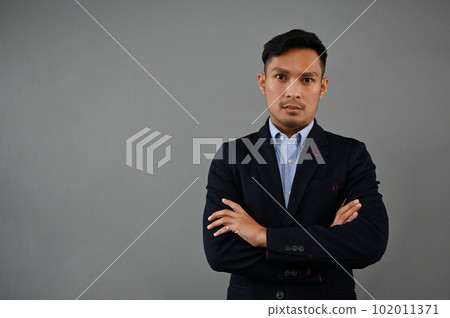 Professional and serious Asian businessman in a formal business suit stands with arms crossed Professional and serious Asian businessman in a formal business suit stands with arms crossed 102011371