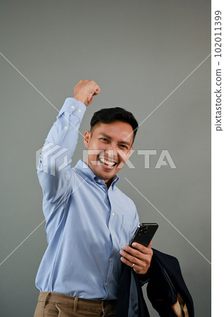 Overjoyed Asian businessman raising his hand, rejoicing, celebrating his success 102011399