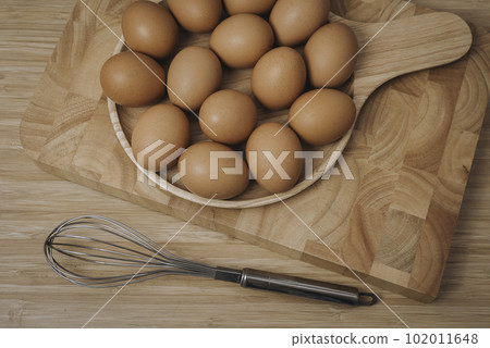 Kitchen metal wire and raw eggs on the wooden board Kitchen metal wire and raw eggs on the wooden board 102011648