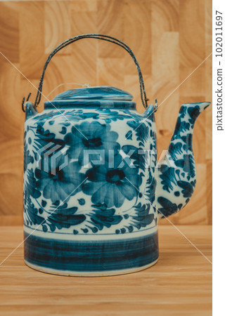 Old Chinese porcelain teapot, with green tea on the wooden Old Chinese porcelain teapot, with green tea on the wooden 102011697