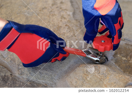 Foreman in protective gloves twists crane with wrench 102012254