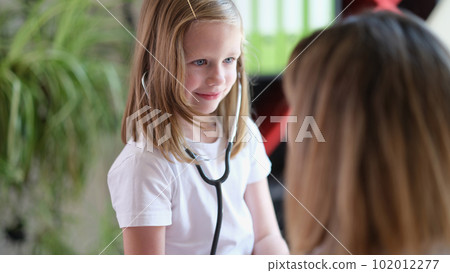 Cute little girl checks organs of woman with stethoscope 102012277