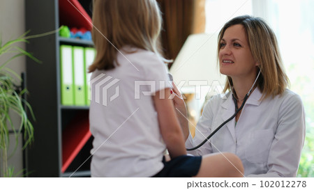 Friendly female doctor checks heartbeat of little patient 102012278
