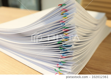 Stack of papers fastened with pins lies on wooden table 102012361