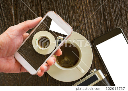 Smart phone and camera with hot tea on wooden table Smart phone and camera with hot tea on wooden table 102013737