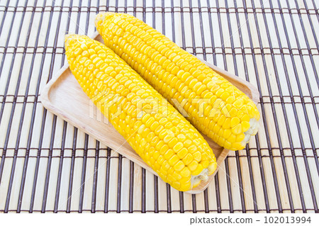 Boiled corn in wooden plate 102013994
