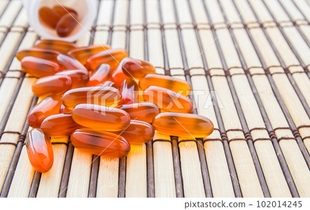 Fish oil capsules on bamboo mat background Fish oil capsules on bamboo mat background 102014245