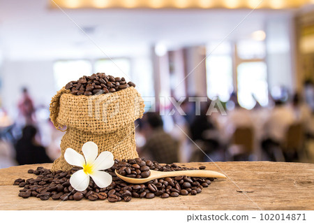 Coffee beans in burlap sack on wooden table wiht blur background Coffee beans in burlap sack on wooden table wiht blur background 102014871
