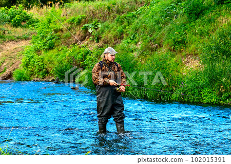 A fisherman catches fish while standing in the water A fisherman catches fish while standing in the water 102015391