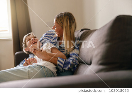 Mother and son plays tickle at home on the sofa living room. Happy motherhood and childhood 102018053
