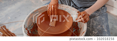 Handmade artist shaping clay bowl with instrument in art studio Handmade artist shaping clay bowl with instrument in art studio 102018158