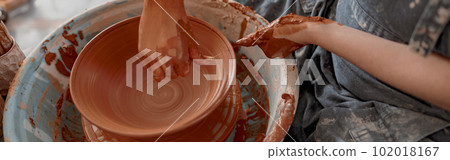 Skillful craftswoman creating earthen bowl on circle in art studio 102018167