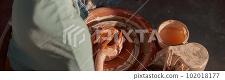 Young potter working on potter wheel in workroom 102018177