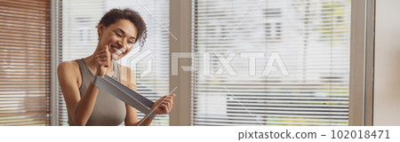 Slim woman doing exercises for hands with elastic band by online tutorials on laptop in living room Slim woman doing exercises for hands with elastic band by online tutorials on laptop in living room 102018471