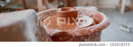 Raw clay product on potter wheel in workshop 102018555