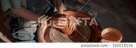 Woman crafter making clay product in pottery room 102018556