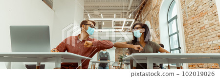 Students siting and greeting bumping elbows at workplace 102019026