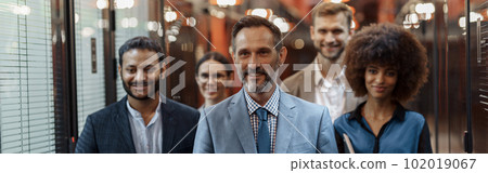 Group of happy, motivated business people standing together at office with their leader 102019067