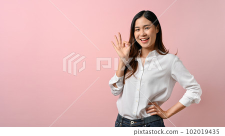 Portrait happy Asian woman shows ok sign on pink isolated background. Portrait happy Asian woman shows ok sign on pink isolated background. 102019435