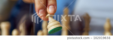 Close up shot of female hand moving chess pieces while playing chess board game Close up shot of female hand moving chess pieces while playing chess board game 102019638