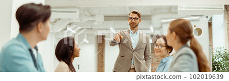 Leader standing in office and explaining new ideas to colleagues Leader standing in office and explaining new ideas to colleagues 102019639