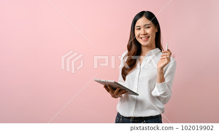 Young Asian woman holding digital tablet while standing with pink isolated background. Young Asian woman holding digital tablet while standing with pink isolated background. 102019902