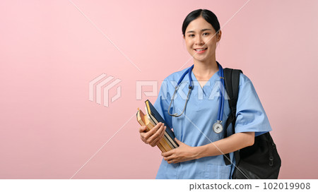 Portrait of young female medical student smiling to the camera while holding textbooks Portrait of young female medical student smiling to the camera while holding textbooks 102019908