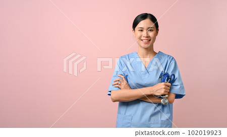 Attractive doctor standing and have her arms crossed against pink isolated background. Attractive doctor standing and have her arms crossed against pink isolated background. 102019923