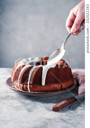 Bundt cake. Drizzling icing on homemade pound, cake.  102021163