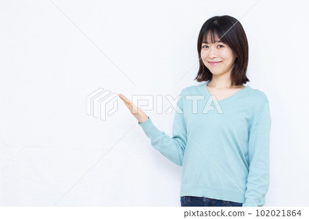 A woman in her thirties introducing in front of a white background 102021864