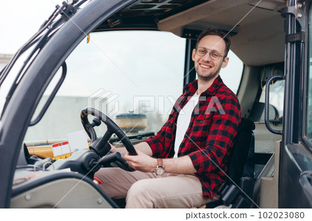 Young Rural Tractor or Combine driver sitting in the cab. Farming and harvesting 102023080