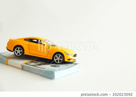 Toy Car Hanging on a Stack of Money on a White Background. Concept Car Expenses, loan payment 102023092