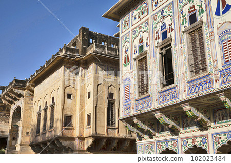 Colourful paintings and wooden windows on the outer wall of Seth Harmukhrai Sanehiram Chokhani Double Haveli, located in Mandawa, Shekhawati, Rajasthan, India Colourful paintings and wooden windows on the outer wall of Seth Harmukhrai Sanehiram Chokhani Double Haveli, located in Mandawa, Shekhawati, Rajasthan, India 102023484