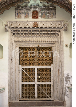 Colourful paintings on the inner wall and wooden door of 1100 Khidkiyon Ki Haveli, owned by Babulal Surana, located in Churu, Shekhawati, Rajasthan, India 102023521
