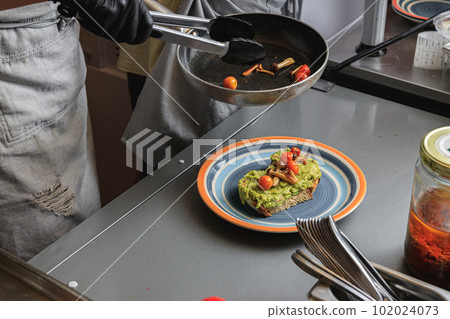 Chef hands cooking avocado toast with vegetables for breakfast menu in restaurant kitchen 102024073