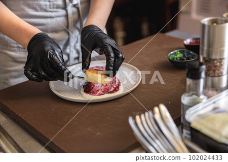 Professional kitchen worker in uniform decorated ready cheesecakes for breakfast in restaurant 102024433