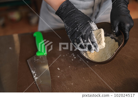 The chef breads the cheese in flour before frying it in a pan in restaurant kitchen The chef breads the cheese in flour before frying it in a pan in restaurant kitchen 102024517