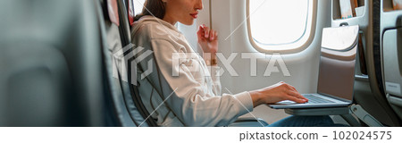 Female traveler using laptop in passenger airplane 102024575