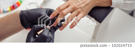 Nail technician applying polish to clients nails in salon Nail technician applying polish to clients nails in salon 102024733