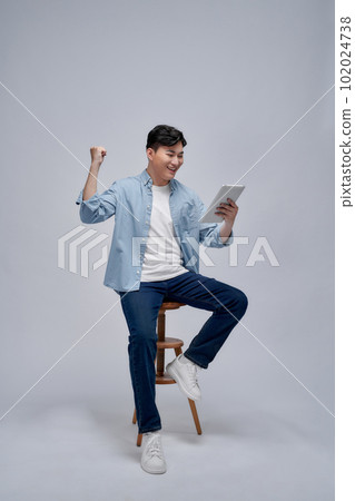 happy excited young man with tablet raised his arm happy excited young man with tablet raised his arm 102024738