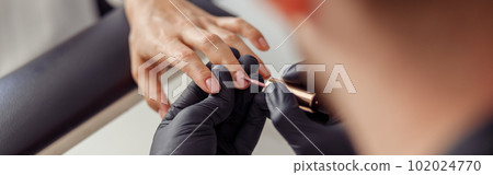 Creative nail master processing nails of his client in salon 102024770