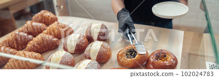 Woman in gloves putting baked goods on snowcase 102024783