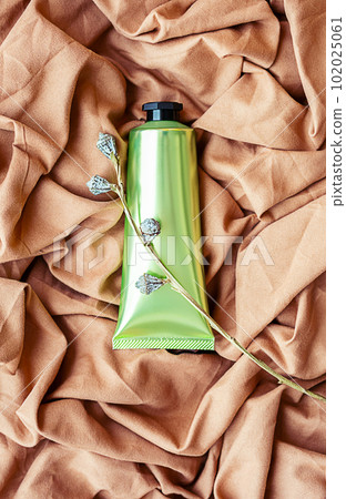 Cosmetic tube on textile background. Skin care beauty product layout. 102025061