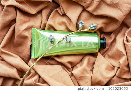 Cosmetic tube on textile background. Skin care beauty product layout. 102025063
