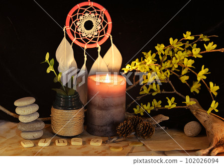 Esoteric and occult still life with vintage magic objects, runes and burning candle on witch table altar for mystic rituals and fortune telling. Halloween and gothic background 102026094