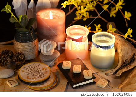 Esoteric and occult still life with vintage magic objects, runes and burning candles on witch table altar for mystic rituals and fortune telling. Halloween and gothic background 102026095